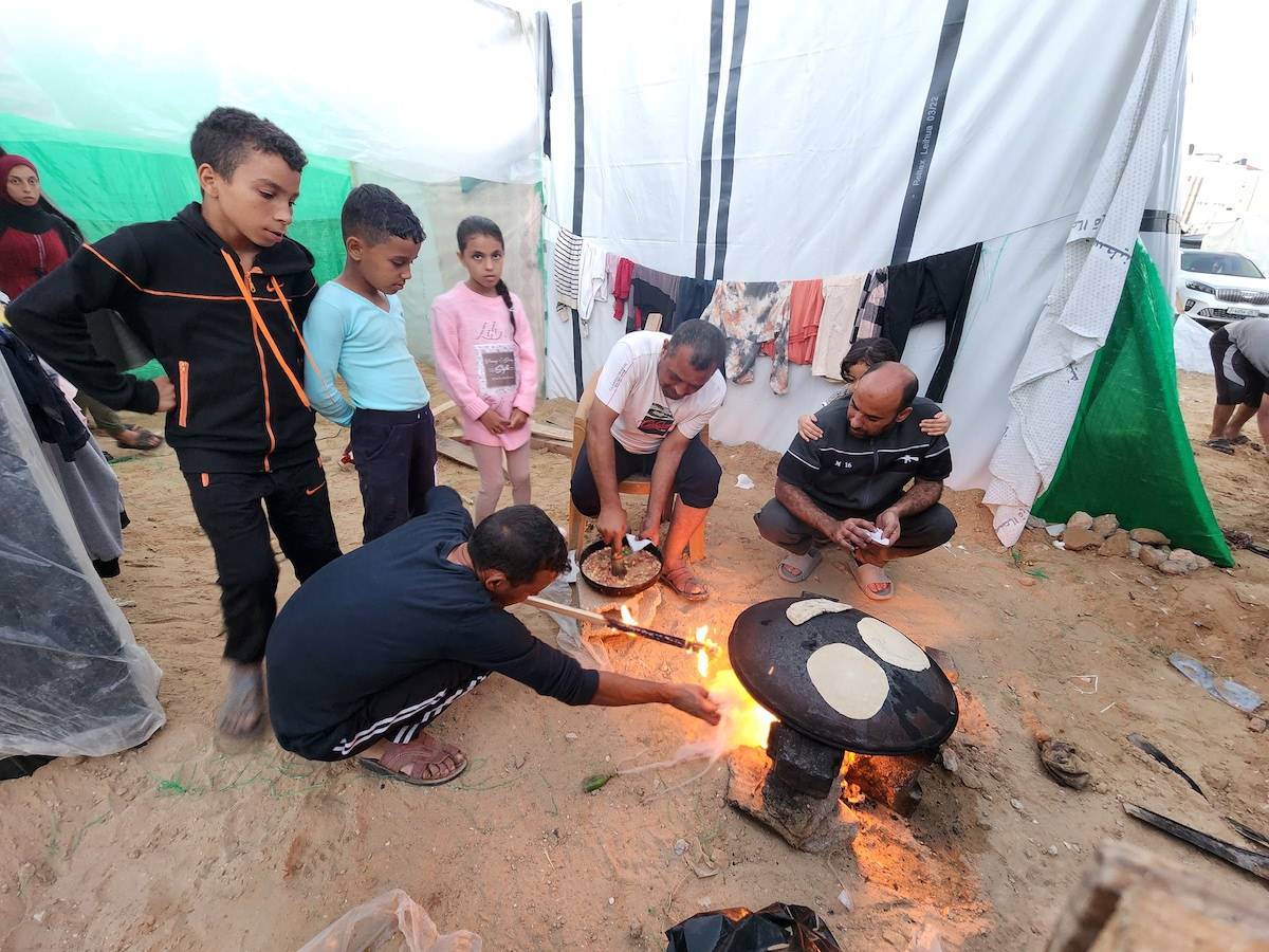 Palestinians, who migrate to the southern and central parts of the Gaza Strip due to Israeli attacks, cook after they set up tents around the Al-Aqsa Martyrs Hospital for shelter in Deir Al-Balah, Gaza on November 15, 2023. [Ashraf Amra - Anadolu Agency]