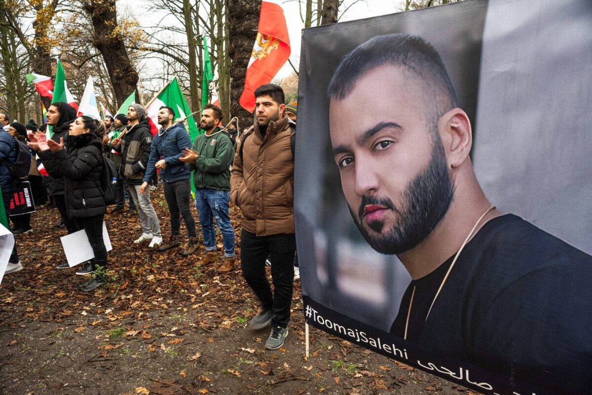 Protesters hold flags and posters of Iranian hip-hop artist