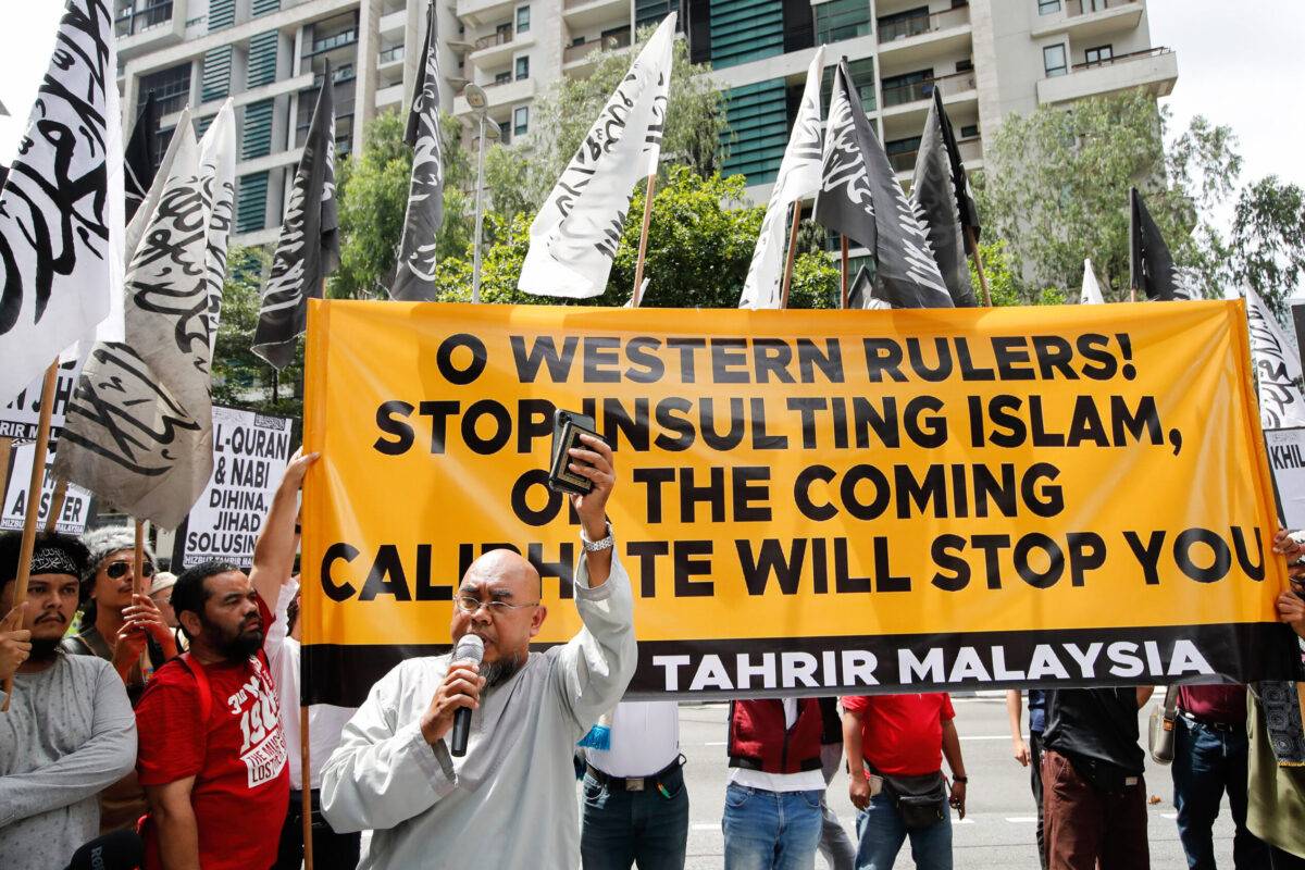 A Malaysian Muslim holds a copy of the Quran while speaking