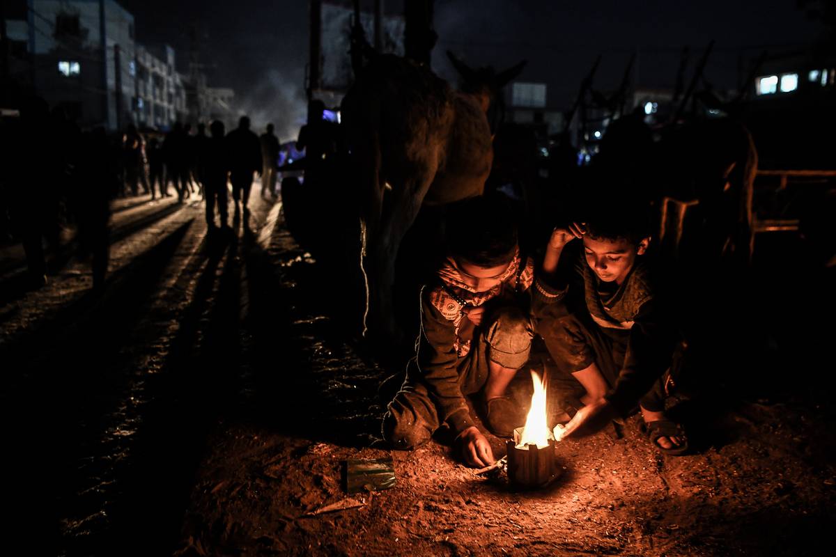 Palestinian children light fire to keep themselves warm at night as Palestinian people set up tents around the Nasser Hospital to take shelter and continue their daily lives under difficult conditions due to Israeli attacks in Khan Yunis, Gaza on December 6, 2023 [Abed Zagout - Anadolu Agency]