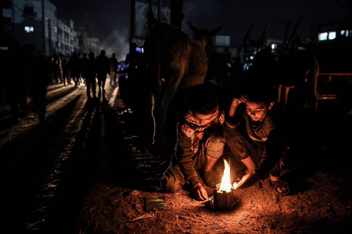 Palestinian children light fire to keep themselves warm at night as Palestinian people set up tents around the Nasser Hospital to take shelter and continue their daily lives under difficult conditions due to Israeli attacks in Khan Yunis, Gaza on December 6, 2023 [Abed Zagout/Anadolu Agency]