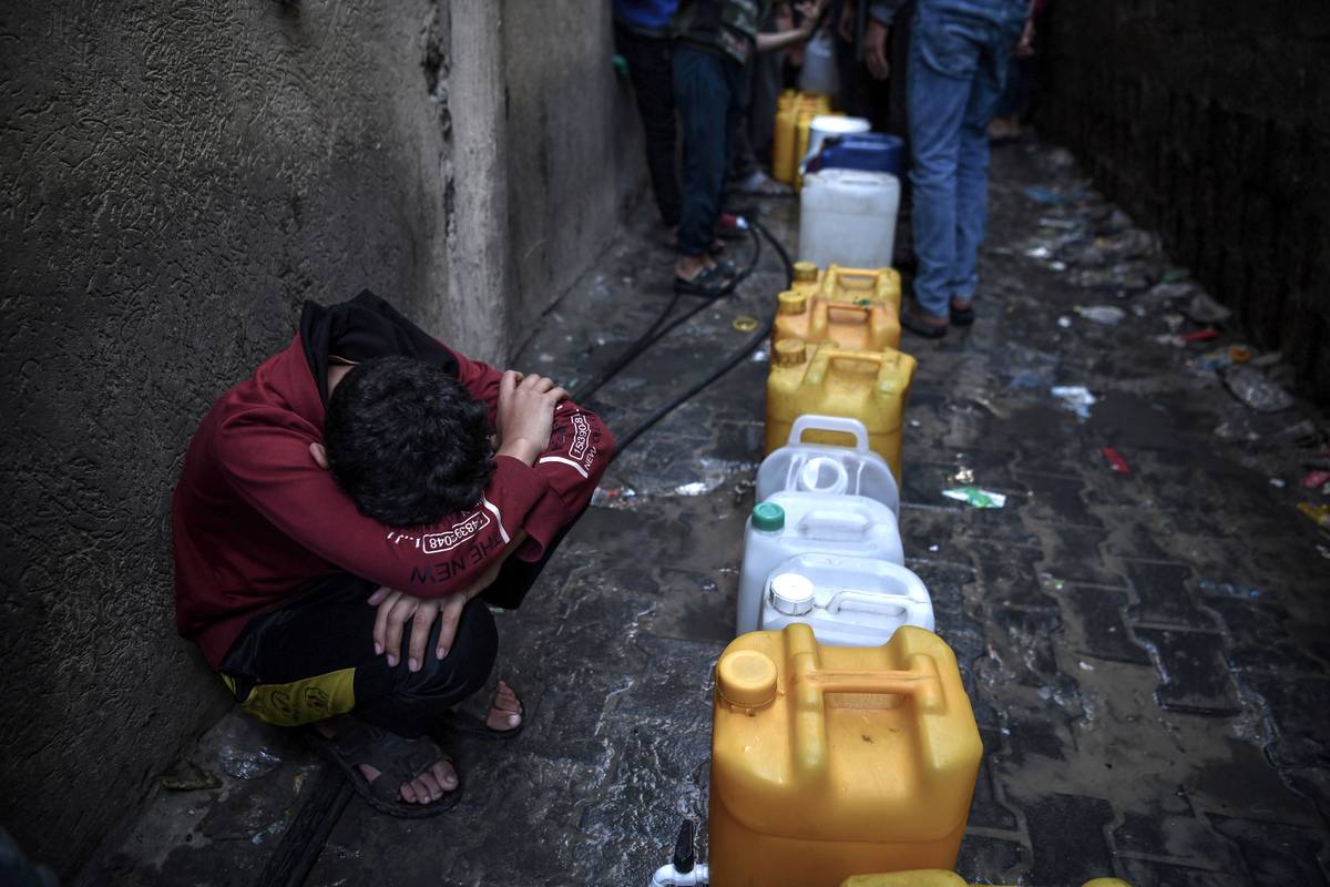 A child waits near galloons as Palestinians wait in line to meet their water needs from mobile tanks, which arrived in certain times, after the great damage to the city's infrastructure due to Israeli attacks in Khan Yunis, Gaza on December 09, 2023 [Abed Zagout - Anadolu Agency]