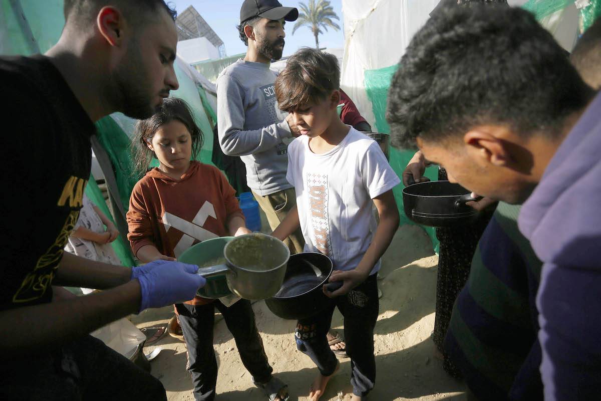 Displaced Palestinians, living in a tent camp in the city of Deir Al Balah, struggling with limited resources and difficult conditions, wait to receive soup distributed by volunteers in Deir Al-Balah, Gaza on December 16, 2023. [Ashraf Amra - Anadolu Agency]