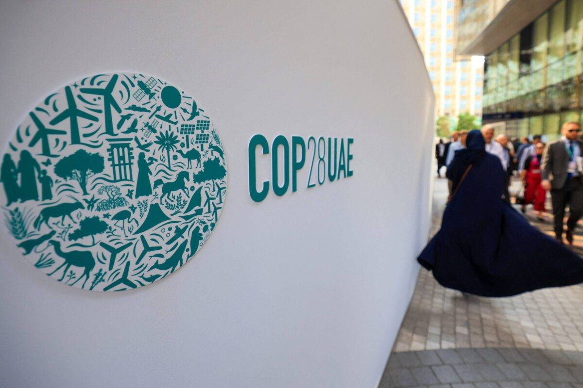 People walk past a COP28 sign at the Expo City during the United Nations climate summit in Dubai on December 5, 2023 [KARIM SAHIB/AFP via Getty Images]