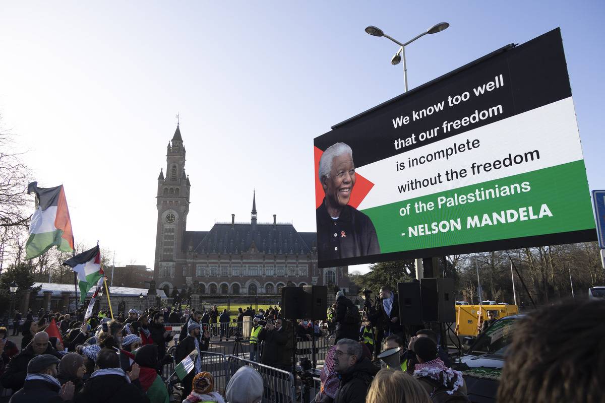 A view of giant screen showing Nelson Mandela's quote as people, holding Palestinian flags, gather outside the International Court of Justice during the session on the day the International Court of Justice (ICJ) rule on Gaza genocide case against Israel made by South Africa in the Hague, the Netherlands on January 26, 2024. [Nikos Oikonomou - Anadolu Agency]