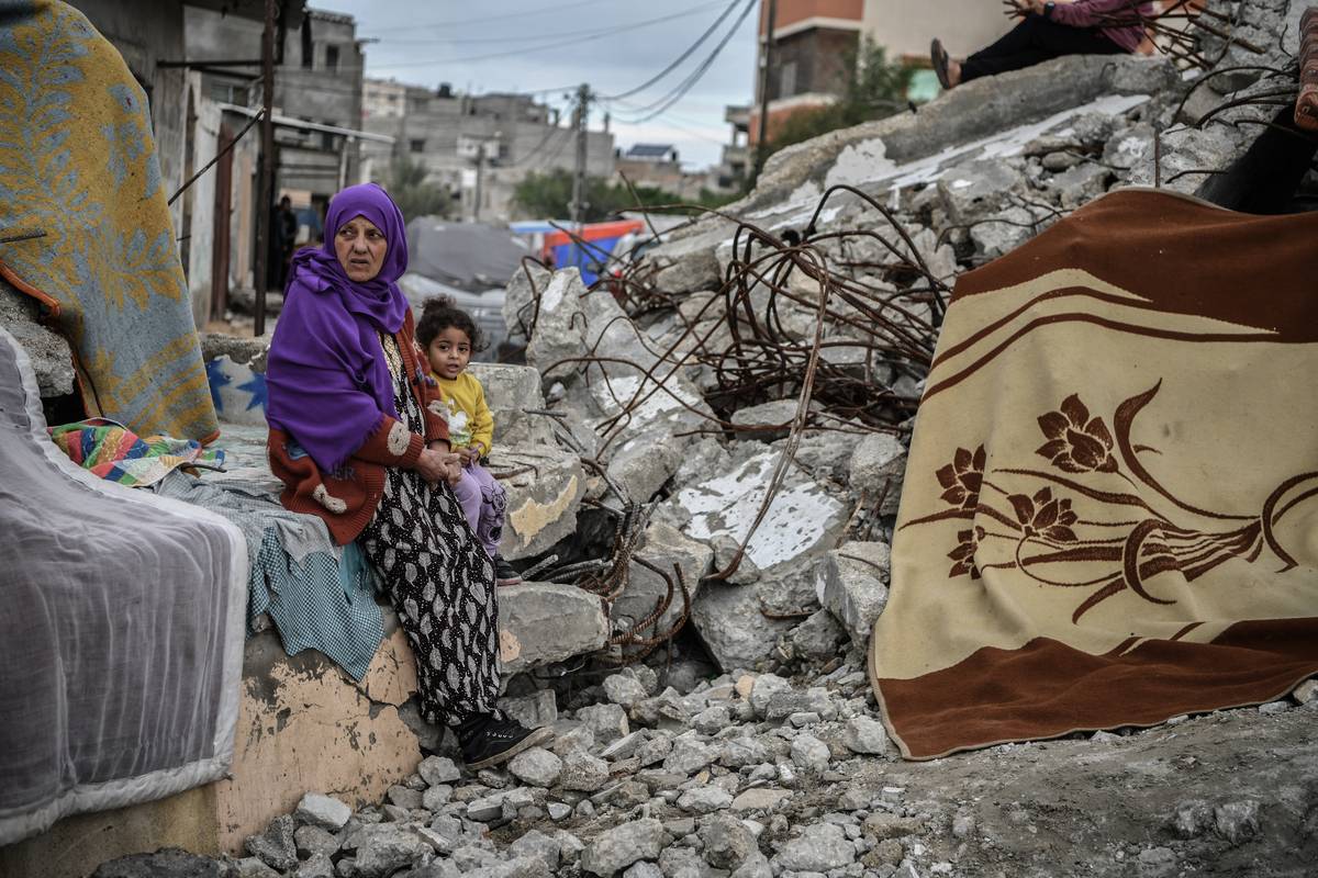 A woman and a child sit among a debris of a collapsed structure at the area where displaced Palestinian families who took refuge in Rafah, Gaza continue to live under difficult winter conditions in makeshift tents on January 28, 2024. [Abed Zagout - Anadolu Agency]