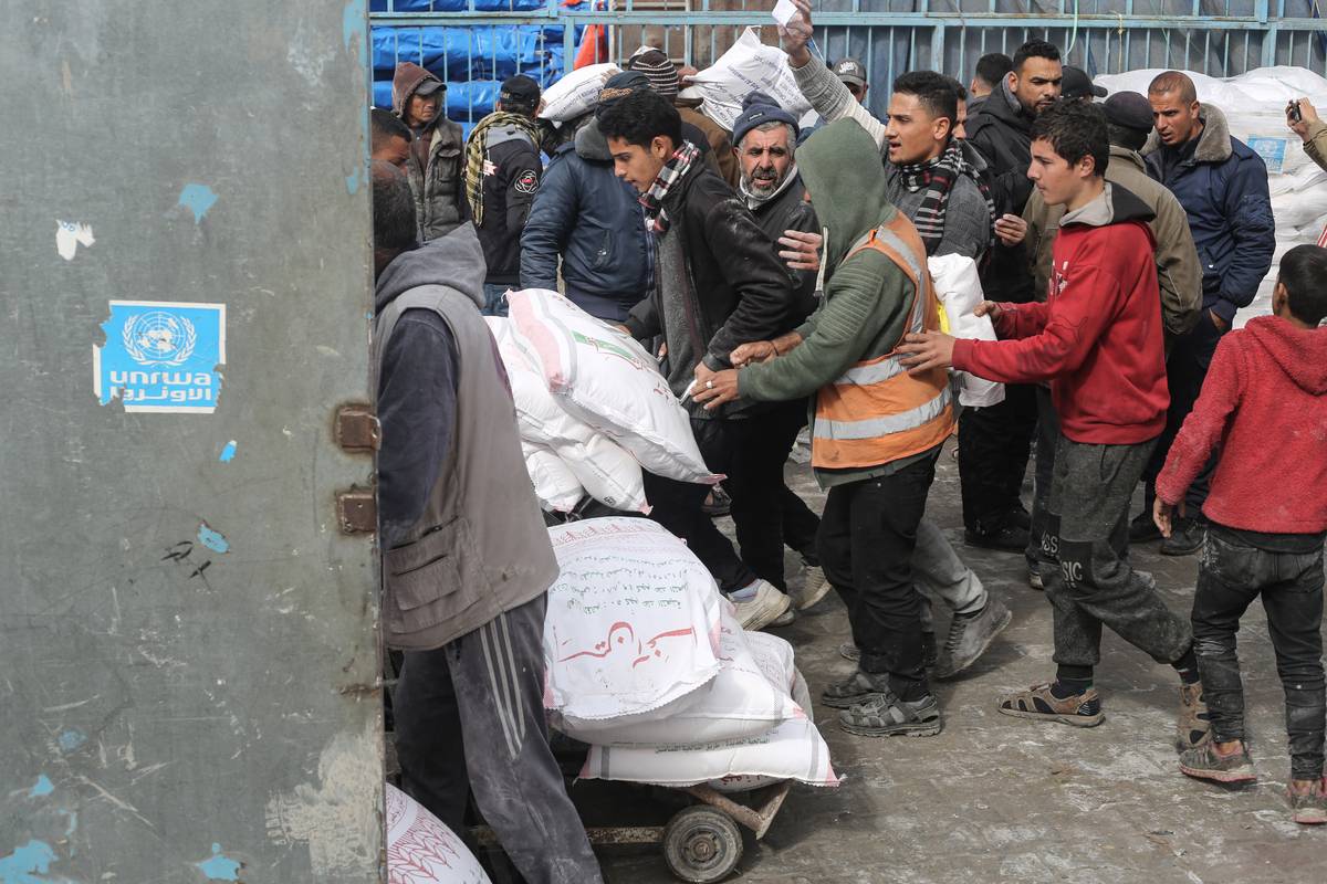 Palestinians, who left their homes and took refuge in Rafah city under hard conditions, carry the flour they received at the area where UNRWA (The United Nations Relief and Works Agency for Palestine Refugees) distributes flour to families as Israeli attacks continue in Rafah of Gaza on January 28, 2024. [Ahmed Zaqout - Anadolu Agency]