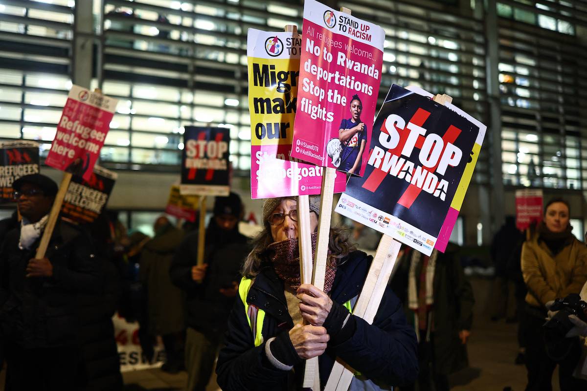 Demonstrators hold placards during a protest against the British Government's latest plan to deport immigrants to Rwanda, outside the Home Office in central London on December 18, 2023. [ HENRY NICHOLLS / AFP) (Photo by HENRY NICHOLLS/AFP via Getty Images]