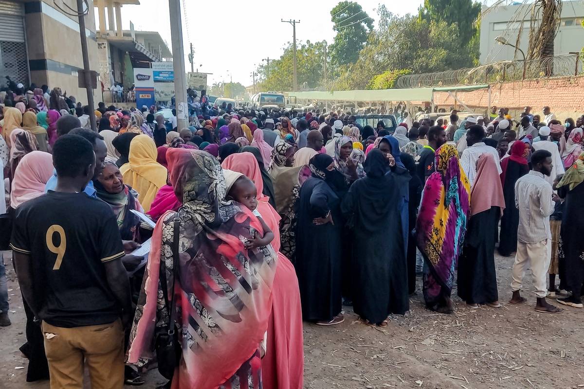 People from states of Khartoum and al-Jazira, displaced by the ongoing conflict in Sudan between the army and paramilitaries, queue to receive aid from a charity organisation in Gedaref on December 30, 2023. [Photo by -/AFP via Getty Images]