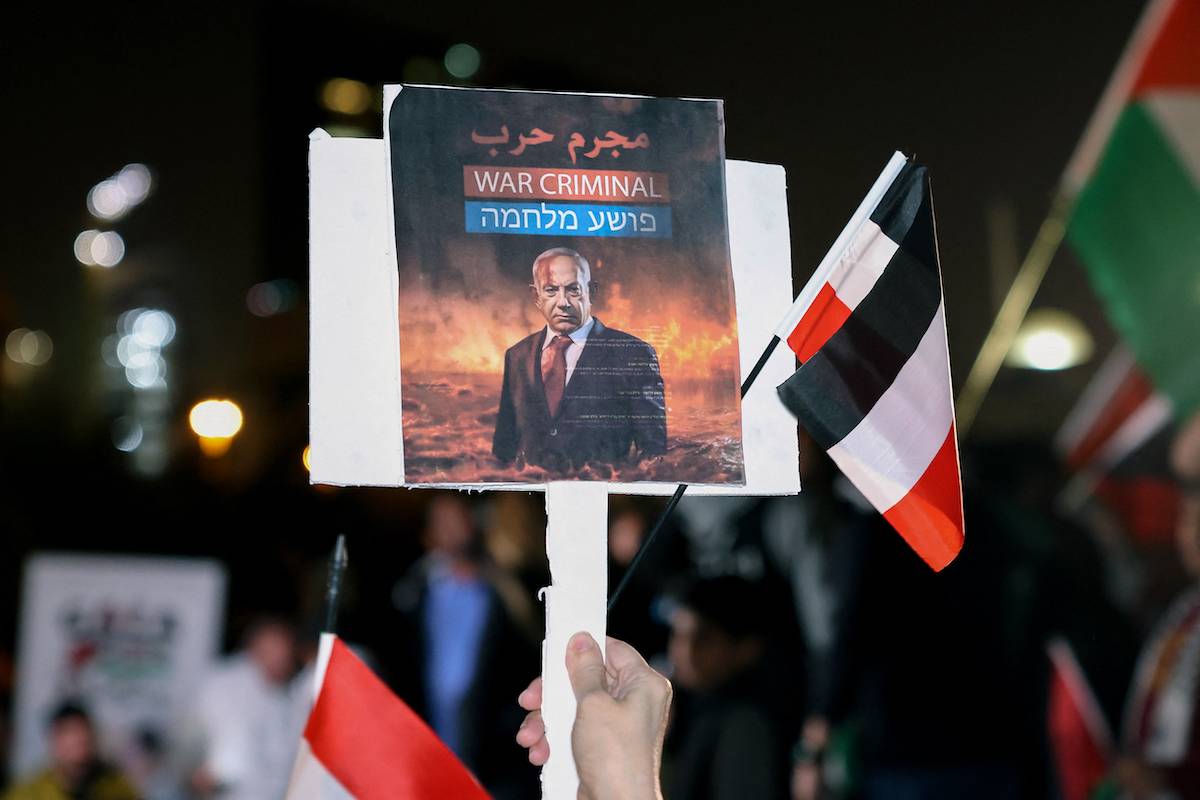 A Kuwaiti man holds a placard bearing the portrait of Israeli Prime Minister Benjamin Netanyahu during a rally in solidarity with the people of Gaza at Iradah Square in Kuwait City on January 14, 2024, as the ongoing war between Israel and Hamas enters its 100th day. [YASSER AL-ZAYYAT/AFP via Getty Images]