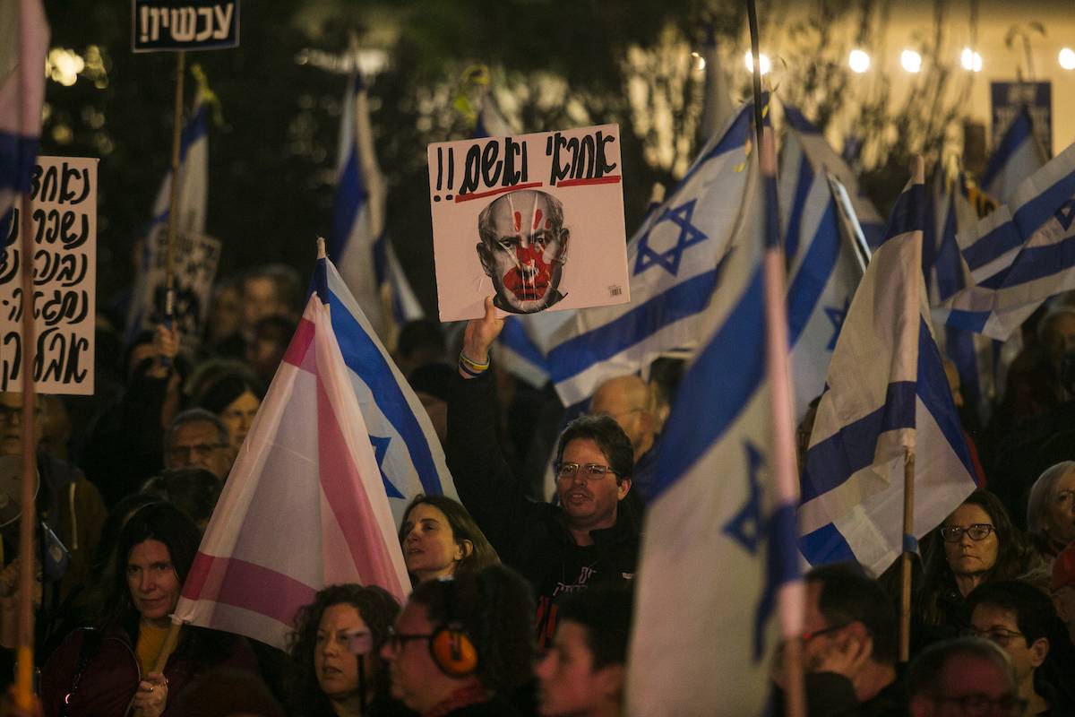 Protesters hold signs and flags during a demonstration against Israeli Prime Minister Benjamin Netanyahu and the Israeli government on January 27, 2024 in Tel Aviv, Israel. [Amir Levy/Getty Images]