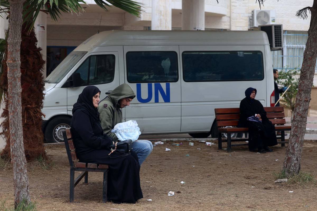 Displaced Palestinian people sit on benches as they wait outside a clinic of the United Nations Relief and Works Agency for Palestine Refugees (UNRWA) in Rafah in the southern Gaza Strip on January 28, 2024 [AFP via Getty Images]