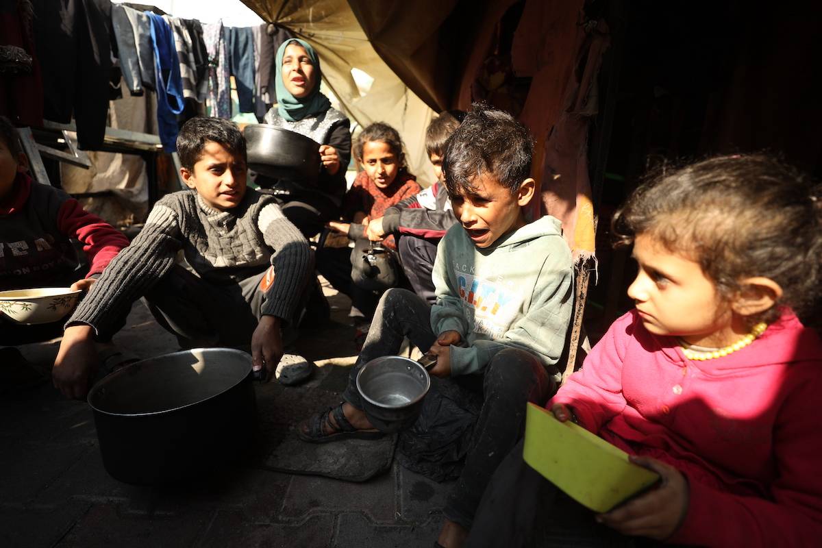 Palestinian children wait for the food with pots as Palestinian people survive under difficult conditions at Jabalia Refugee Camp in Gaza on February 26, 2024. [Dawoud Abo Alkas - Anadolu Agency]