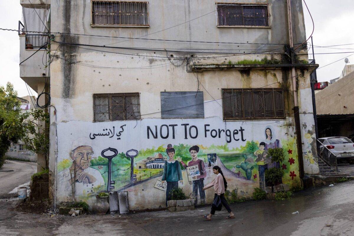 A girl passes by graffiti referring to the Nakba on a damaged house in Jenin, Occupied West Bank on December 31, 2023 [Maja Hitij/Getty Images]