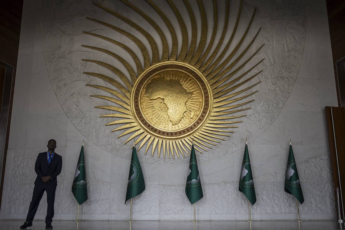 A security guard stands next to an AU logo at the entrance of the main plenary hall during the second day of the 37th Ordinary Session of the Assembly of the African Union (AU) at the AU headquarters in Addis Ababa on February 18, 2024. [MICHELE SPATARI/AFP via Getty Images]
