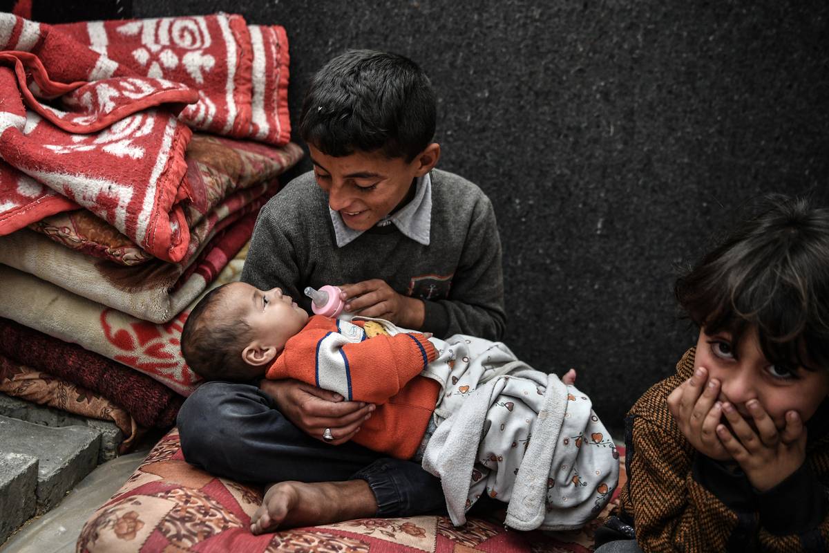 11-year-old Muhammed Zurub takes care of his infant brother as Palestinian Zurub family leaving their homes and taking refuge in Rafah city to protect themselves from Israeli attacks try to survive under harsh conditions, on February 25, 2024 in Rafah, Gaza. [Abed Zagout - Anadolu Agency]