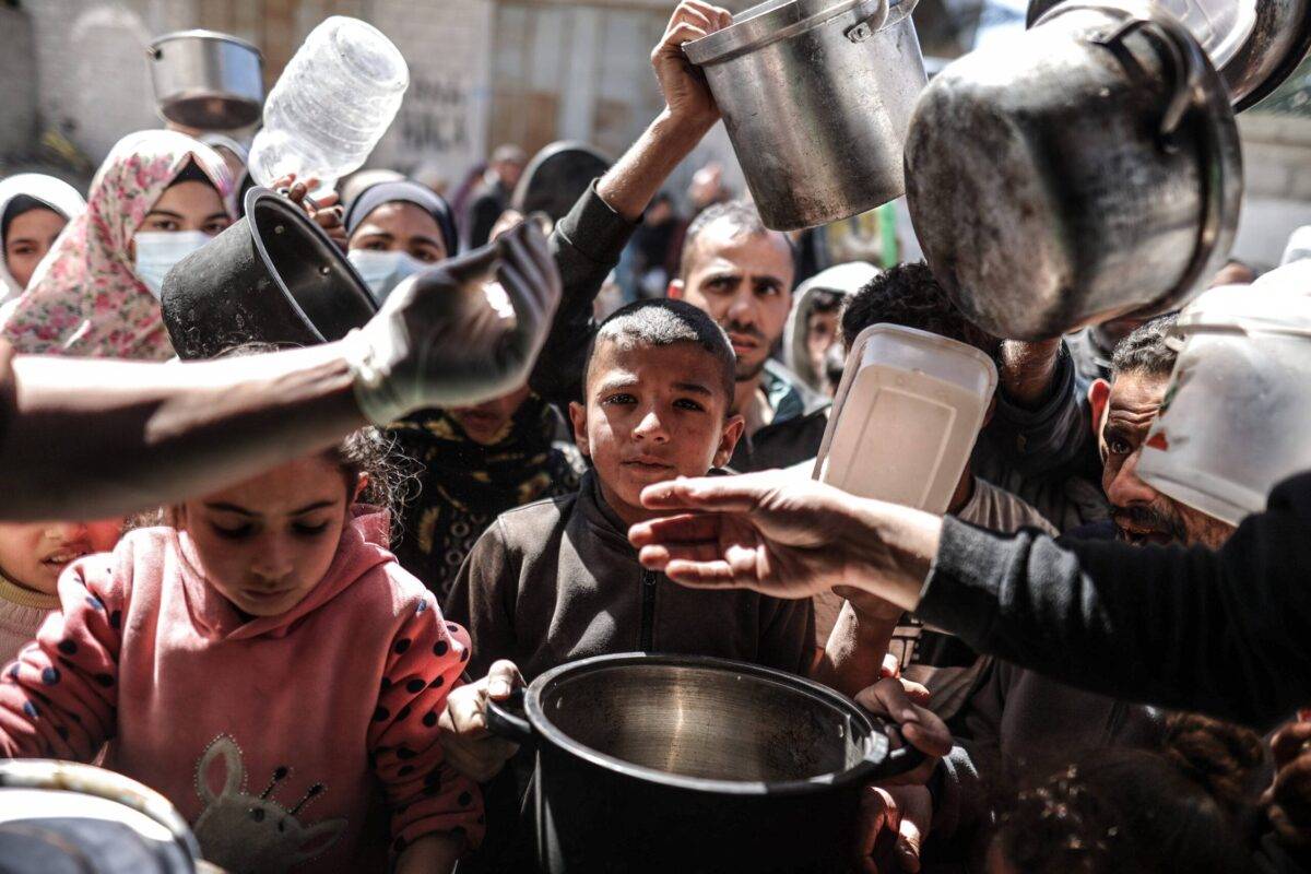 Palestinian people with empty pots receive food distributed by charity as Gaza faces hunger crisis as situation worsens amid blockade due to the ongoing Israeli offensive in Deir al Balah, central Gaza on February 29, 2024 [Ali Jadallah/Anadolu Agency]