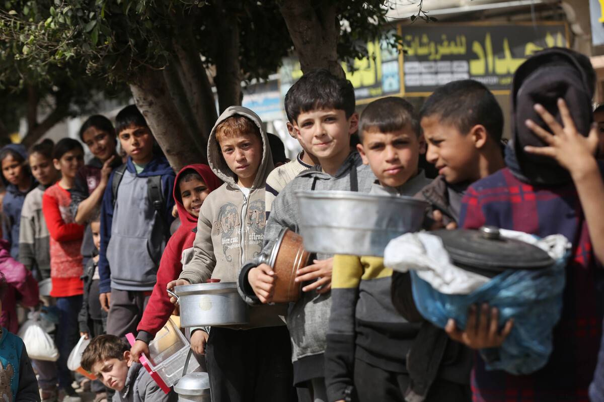 Palestinians queue for hours to receive food distributed by charitable organizations, in Deir Balah, Gaza on March 01, 2024. [Ashraf Amra - Anadolu Agency]