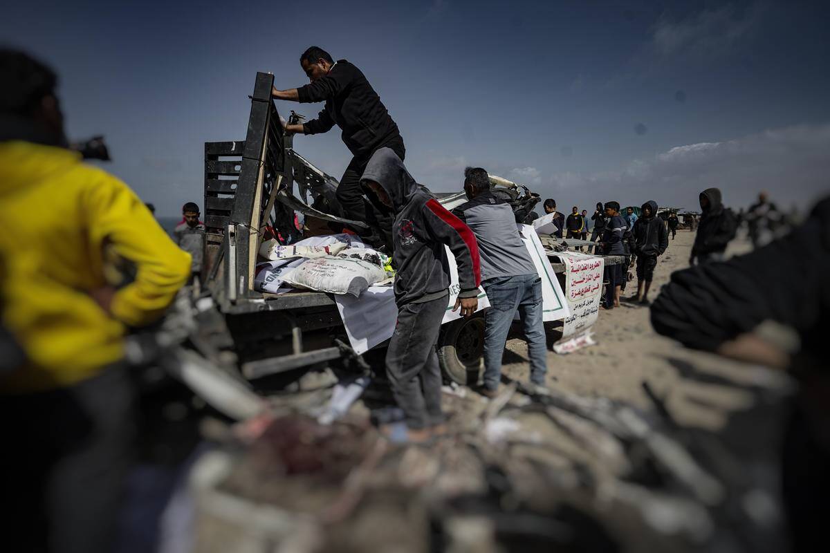 Palestinian people try to remove the debris from a heavily damaged humanitarian aid vehicle, which has been the target of Israeli airstrikes resulting in the death of nine and dozens of injured, in Deir al-Balah, Gaza on March 3, 2024. [Belal Khaled - Anadolu Agency]