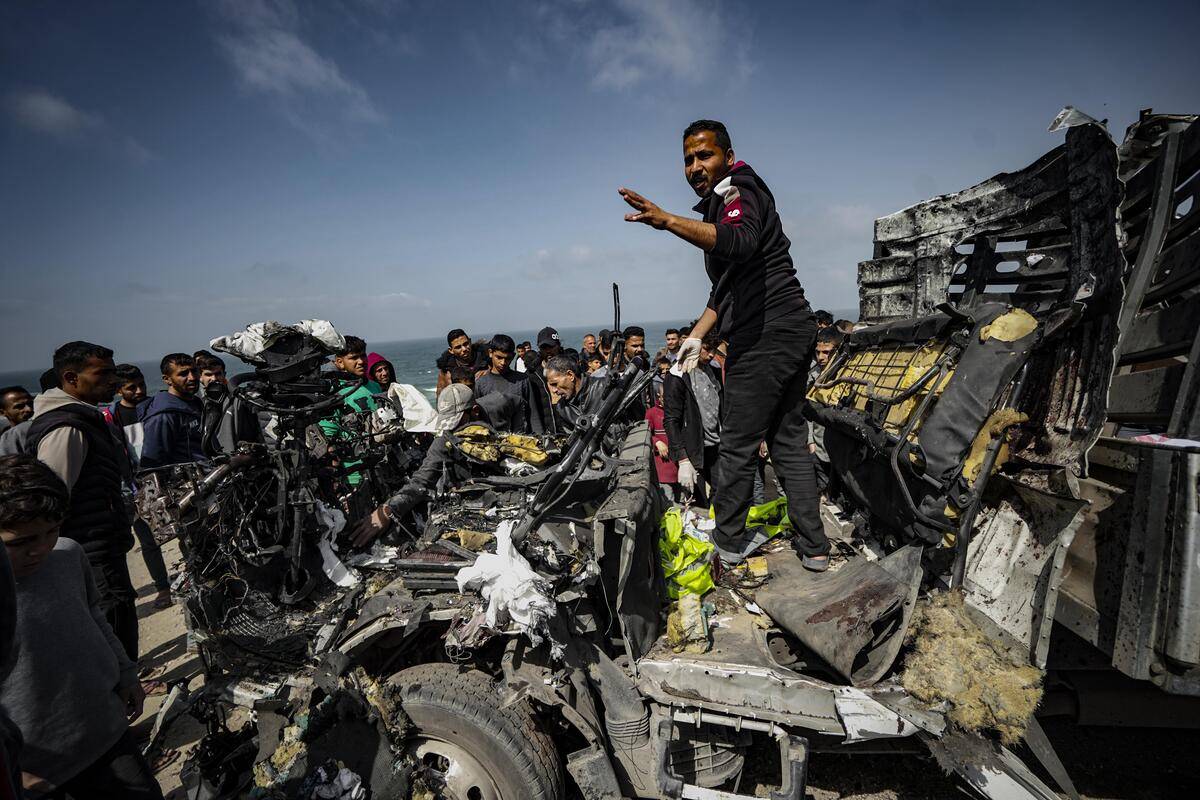 Palestinian people try to remove the debris from a heavily damaged humanitarian aid vehicle, which has been the target of Israeli airstrikes resulting in the death of nine and dozens of injured, in Deir al-Balah, Gaza on March 3, 2024. [Belal Khaled - Anadolu Agency]