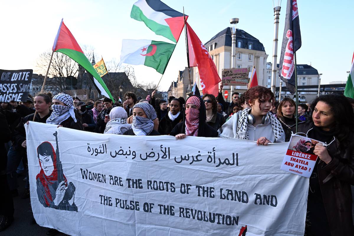 Some protesters hold Palestinian flags in support of Gaza as thousands of people march with banners to protest inequalities against women during International Women's Day in Brussels, Belgium on March 08, 2024. [Dursun Aydemir - Anadolu Agency]