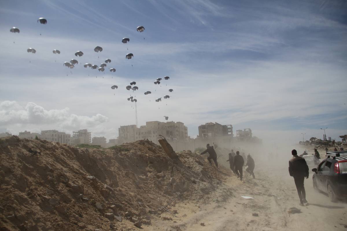 Humanitarian aid packages are seen landing by the help of parachutes after dropping from a plane as Palestinians are waiting to receive them in Gaza City, Gaza on March 09, 2024. [Mahmud Isa - Anadolu Agency]