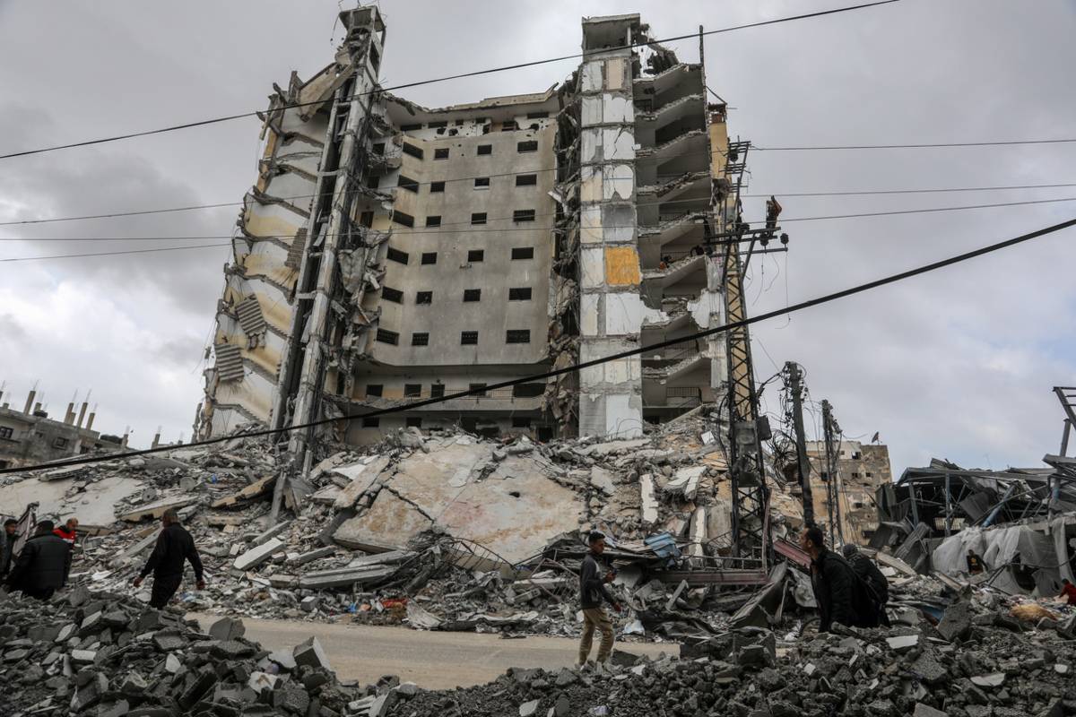 People pass by the damaged Burj al-Masri building and the surroundings after Israeli attacks in Rafah City of Gaza on March 18, 2024. [Abed Rahim Khatib - Anadolu Agency]