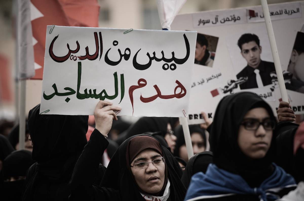 A Bahraini protester holds a placard reading "Demolishing mosques is a sacrilege" as they call for the reconstruction of Shia mosques that were demolished by security forces in 2011 during an anti-regime rally in the village of Diraz, west of Manama, on April 5, 2013. [MOHAMMED AL-SHAIKH/AFP via Getty Images]