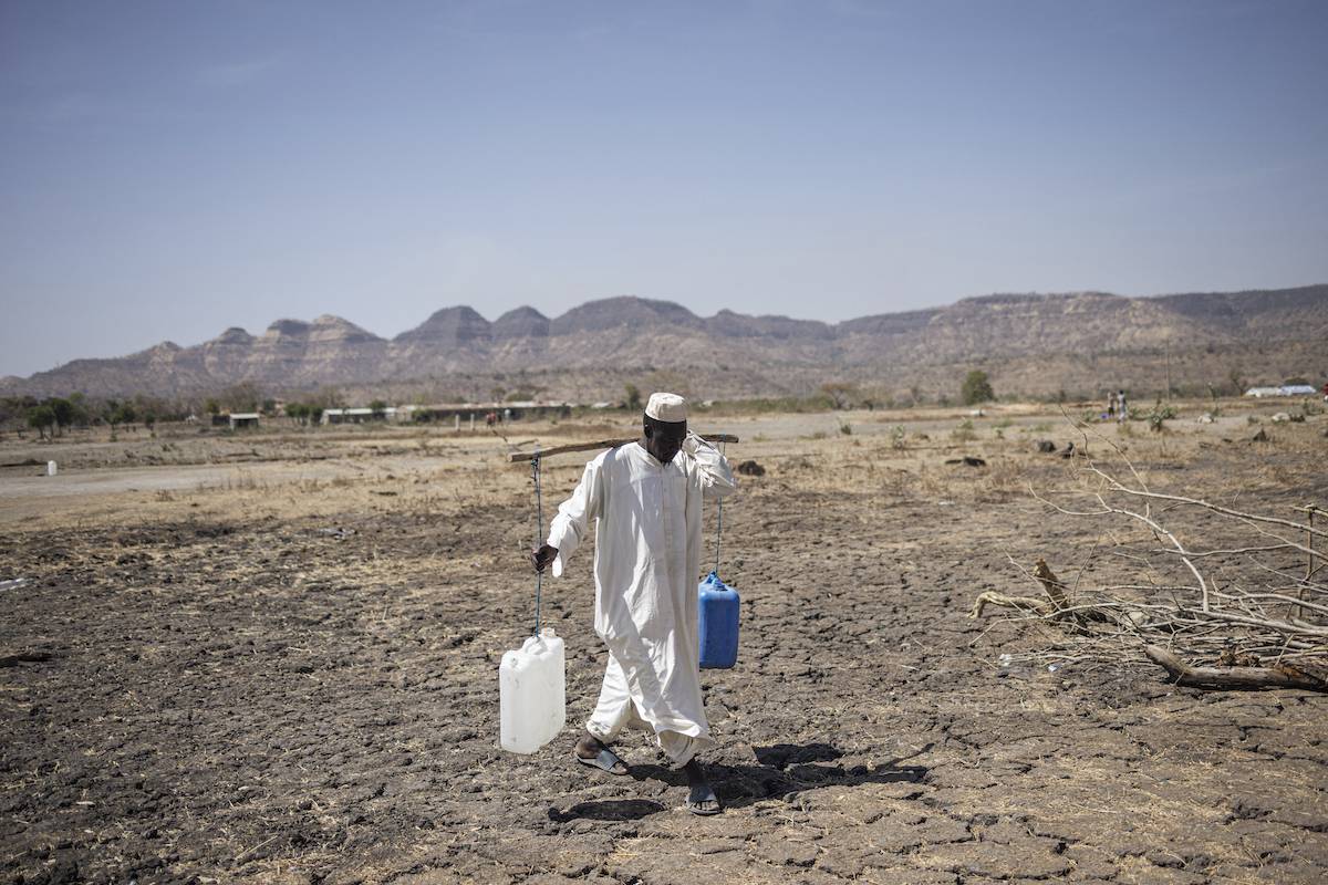 A Sudanese refugee walks back from collecting water in the newly established Awulala refugee camp, near Maganan, 80 km from the Sudanese border in Ethiopia's Amhara region, on February 28, 2024. [MICHELE SPATARI/AFP via Getty Images]