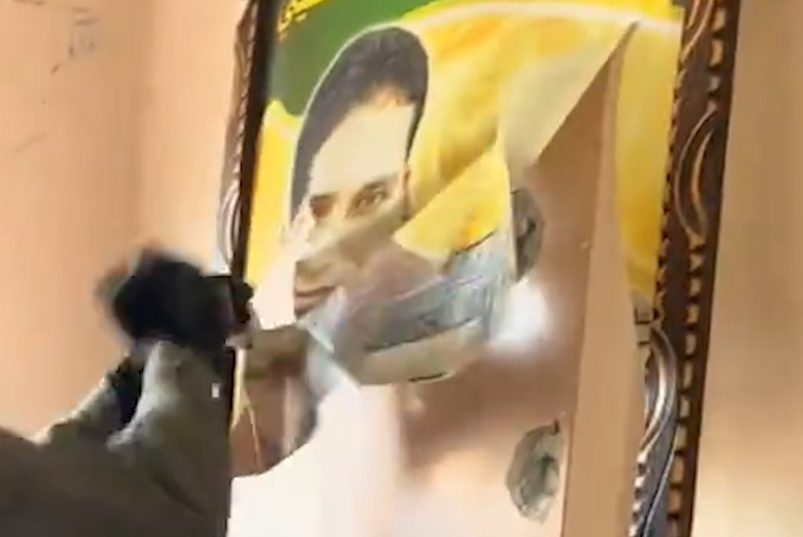 Israeli soldier cuts a memorial picture of a Palestinian journalist killed by Israel in 2014 from inside a home in Gaza