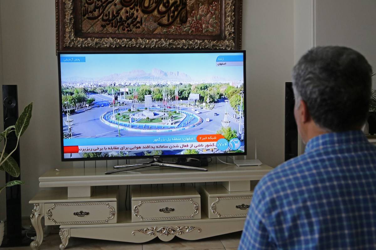 A man watches tv reporter in Tehran, Iran after Iranian official TV confirms 'massive explosions' in central Isfahan province, as US officials confirm Israel carried out strike inside Iran, on April 19, 2024. [Fatemeh Bahrami - Anadolu Agency]