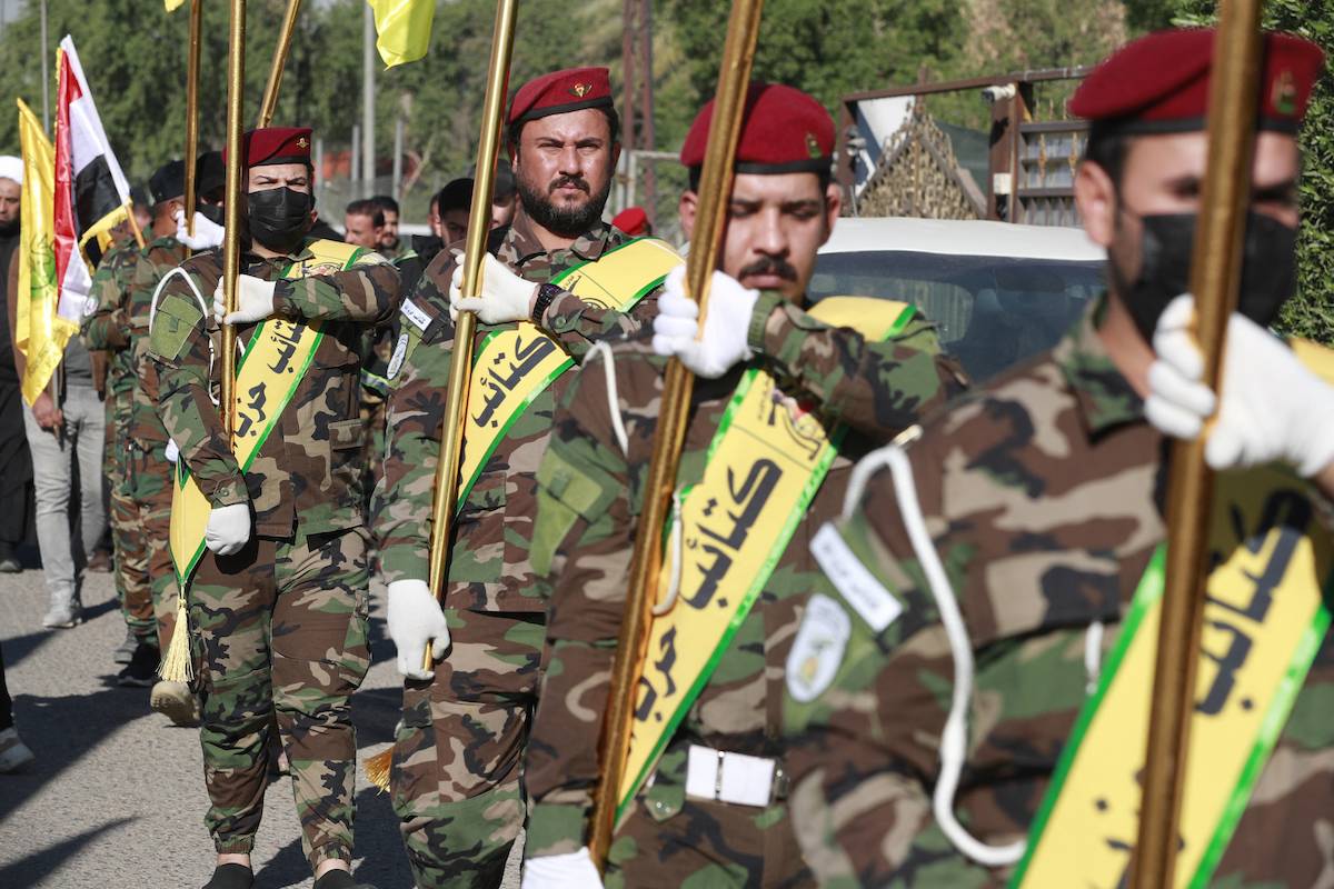 Fighters lift flags of Iraq and paramilitary groups, including al-Nujaba and Kataib Hezbollah, during a funeral in Baghdad for five militants killed a day earlier in a US strike in northern Iraq, on December 4, 2023. [AHMAD AL-RUBAYE/AFP via Getty Images]