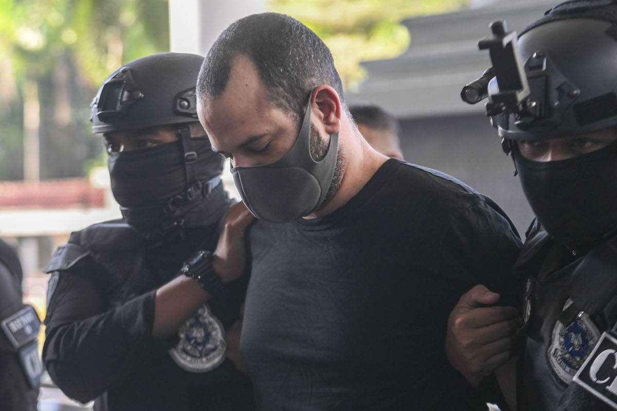 An Israeli man, Shalom Avitan, is being escorted by a police officer as he arrives at the Kuala Lumpur Court Complex in Malaysia on April 12, 2024. [Mat Zain/NurPhoto via Getty Images]