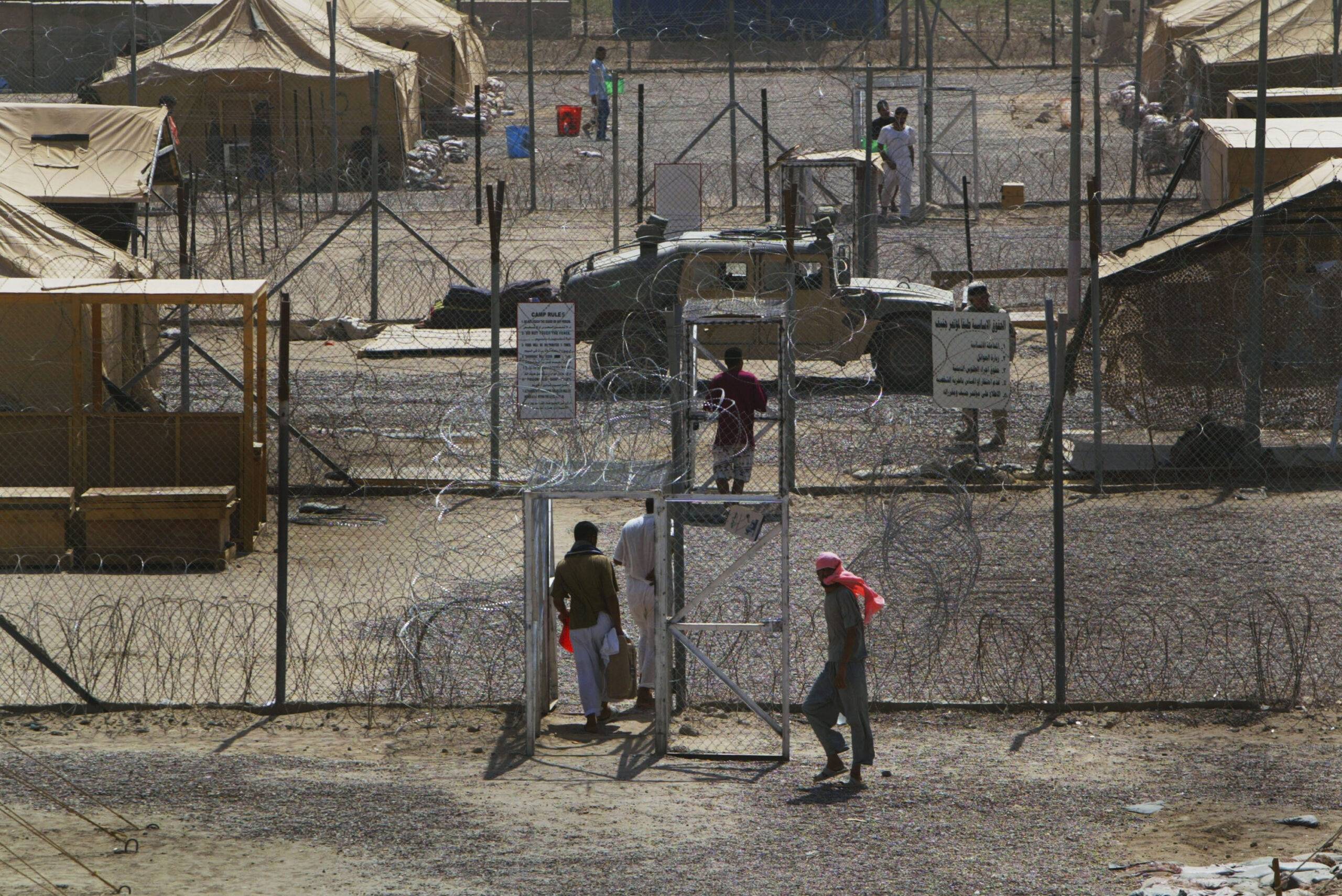 Prisoners mill around in a common area where they are housed in tents, in the Abu Ghraib prison on July 15, 2004 west of Baghdad, Iraq [Joe Raedle/Getty Images]
