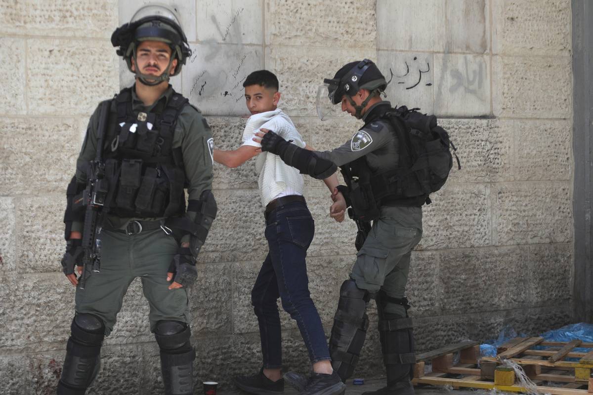 Israeli forces are seen detaining a young Palestinian as fanatical Jewish settlers, who are under the protection of Israeli police, raid on Al-Khalil during the on the third day of the Passover (Pesach) holiday in Bab al-Zawiya, Hebron, West Bank on April 25, 2024. [Mamoun Wazwaz - Anadolu Agency]