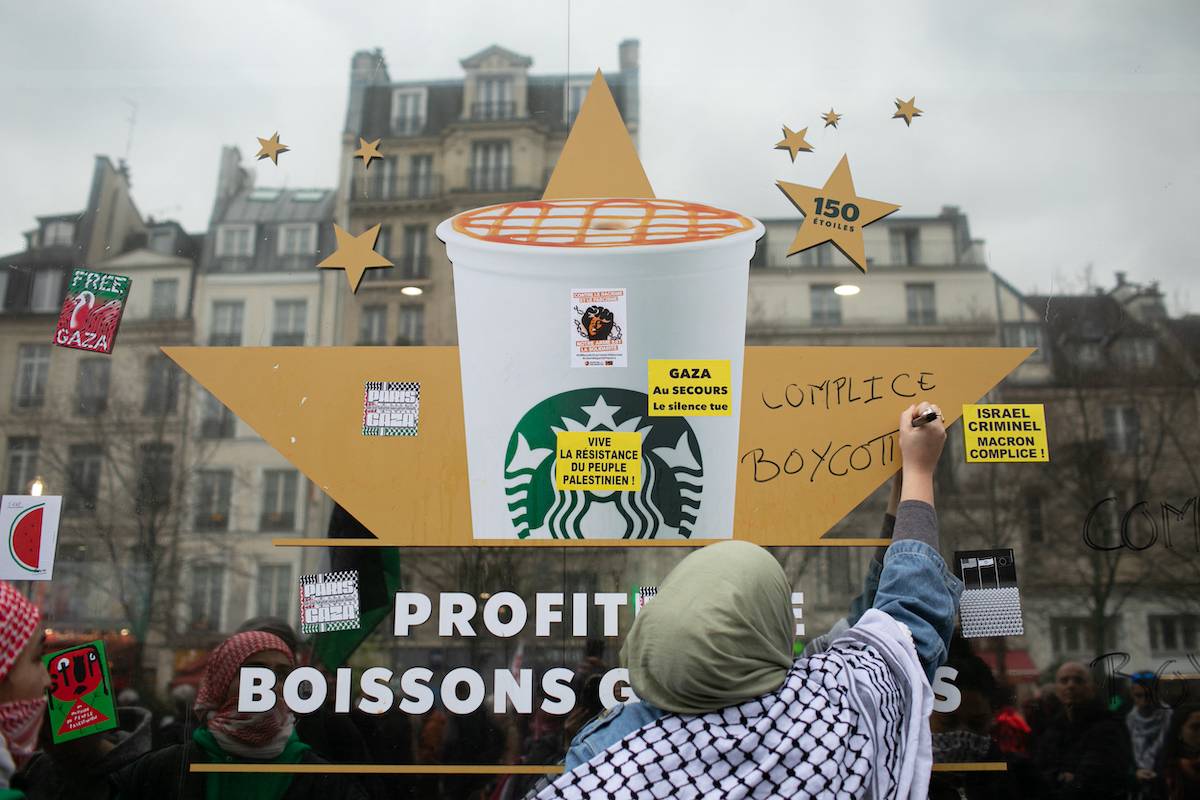 A woman writes complicit, boycott on a Starbucks at the demonstration in support of the Palestinian people in Paris, France on March 30, 2024. [VICTORIA VALDIVIA/Hans Lucas/AFP via Getty Images]