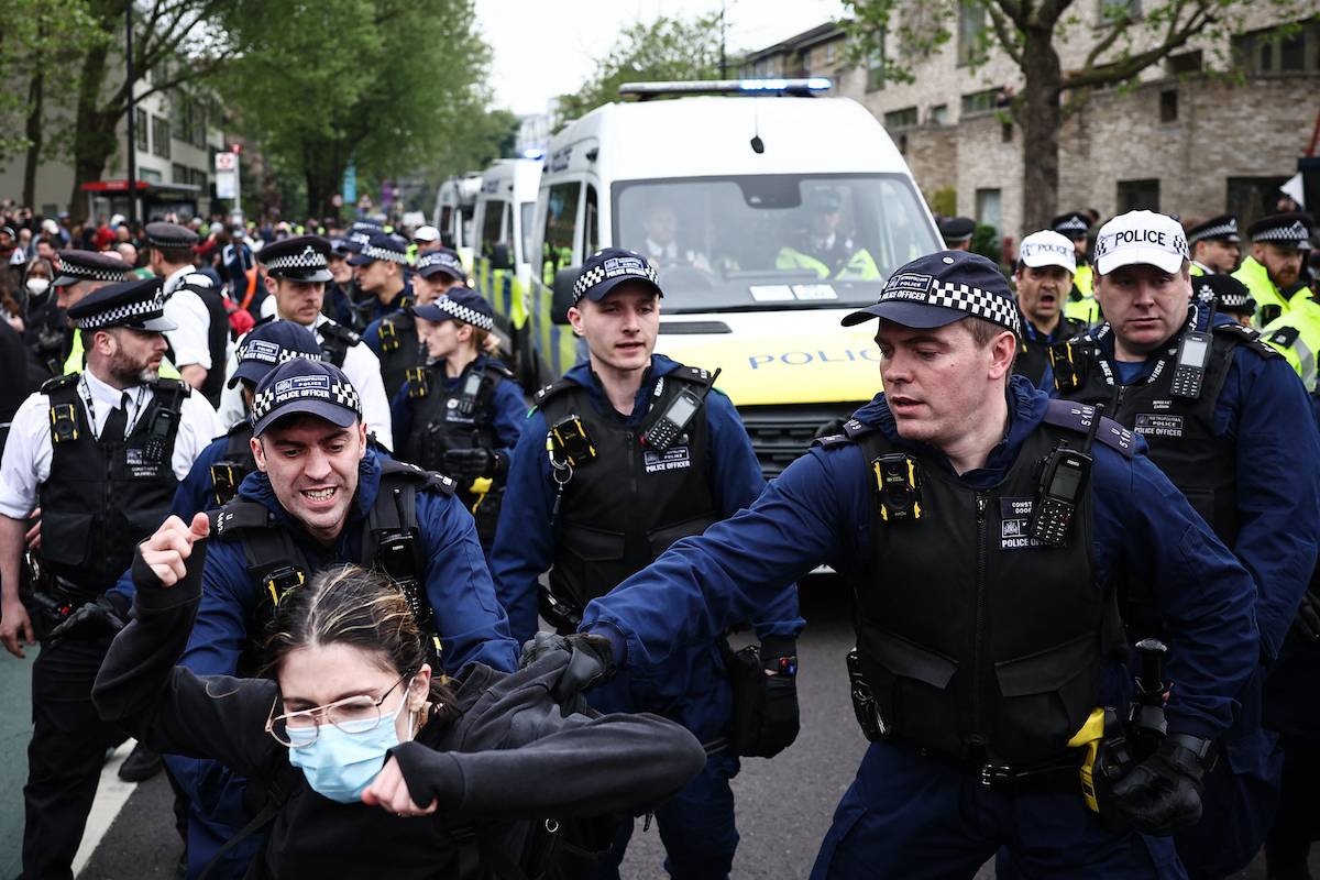 Metropolitan Police officers (MET) arrest protesters taking part in a gathering around a bus reportedly waiting to remove migrants and asylum seekers from a hotel in Peckham, south London, as they block it from transporting them to the Bibby Stockholm barge in Portland, Dorset, south-west England, on May 2, 2024. [HENRY NICHOLLS/AFP via Getty Images]