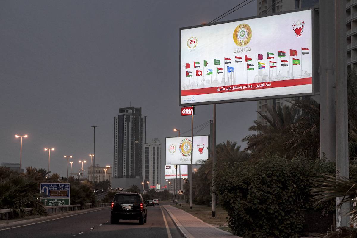 A vehicle moves along a road past a billboard showing the flags of Arab League states ahead of the 33rd Arab League summit in Mamama on May 15, 2024. [MAZEN MAHDI/AFP via Getty Images]