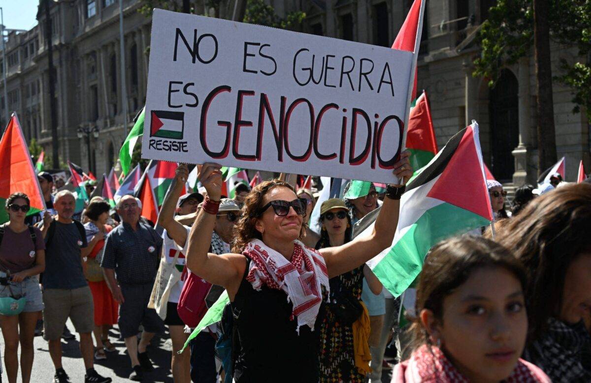 A demonstrator holds a sign reading "It is not war, it is genocide" during a march in Santiago on March 17, 2024 in support of Palestinians amid ongoing battles between Israel and the militant Hamas group in the Gaza Strip. (Photo by RODRIGO ARANGUA / AFP) (Photo by RODRIGO ARANGUA/AFP via Getty Images)