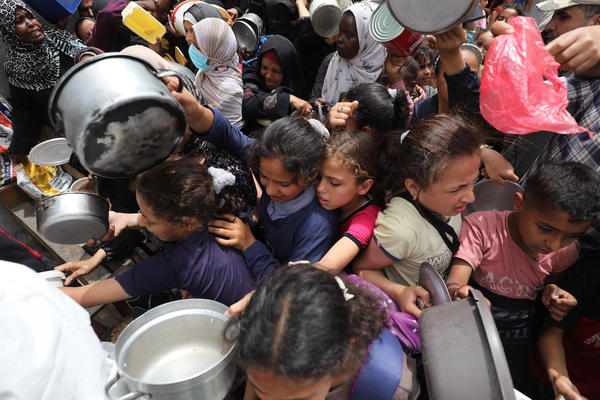 Palestinians, mainly children, wait with empty pots to get food distributed by charitable organizations as food crisis worsens due to the ongoing Israeli blockade, in Nuseirat, Gaza on May 12, 2025. [Moiz Salhi - Anadolu Agency]