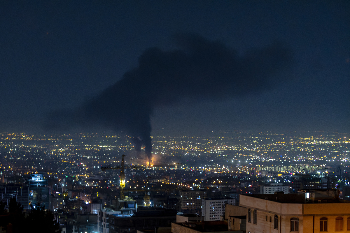 Smoke rises in the distance following an Israeli airstrike in Tehran, Iran, on June 14, 2025. [Photo by KHOSHIRAN/Middle East Images/AFP via Getty Images]
