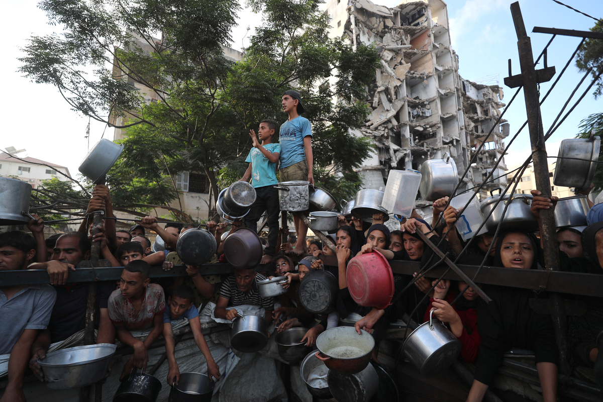 Palestinians, including children struggle to receive hot meals distributed by a local charity in Gaza City on July 14, 2025. [Mahmoud İssa - Anadolu Agency]