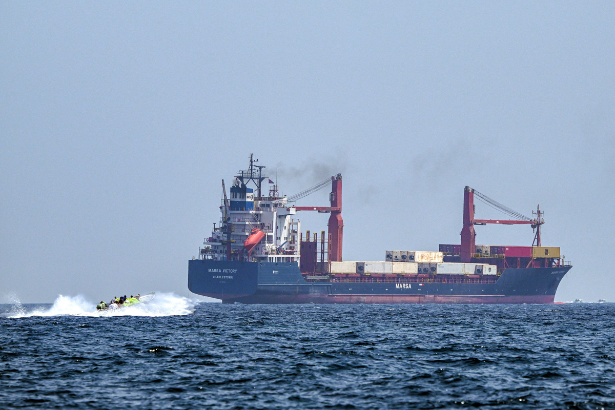 A boat approaches the St Kitt's and Nevis-flagged container ship Marsa Victory while crusing in the waters of the Strait of Hormuz off the coast of Khasab in Oman's northern Musandam peninsula on June 25, 2025. [Photo by GIUSEPPE CACACE/AFP via Getty Images]
