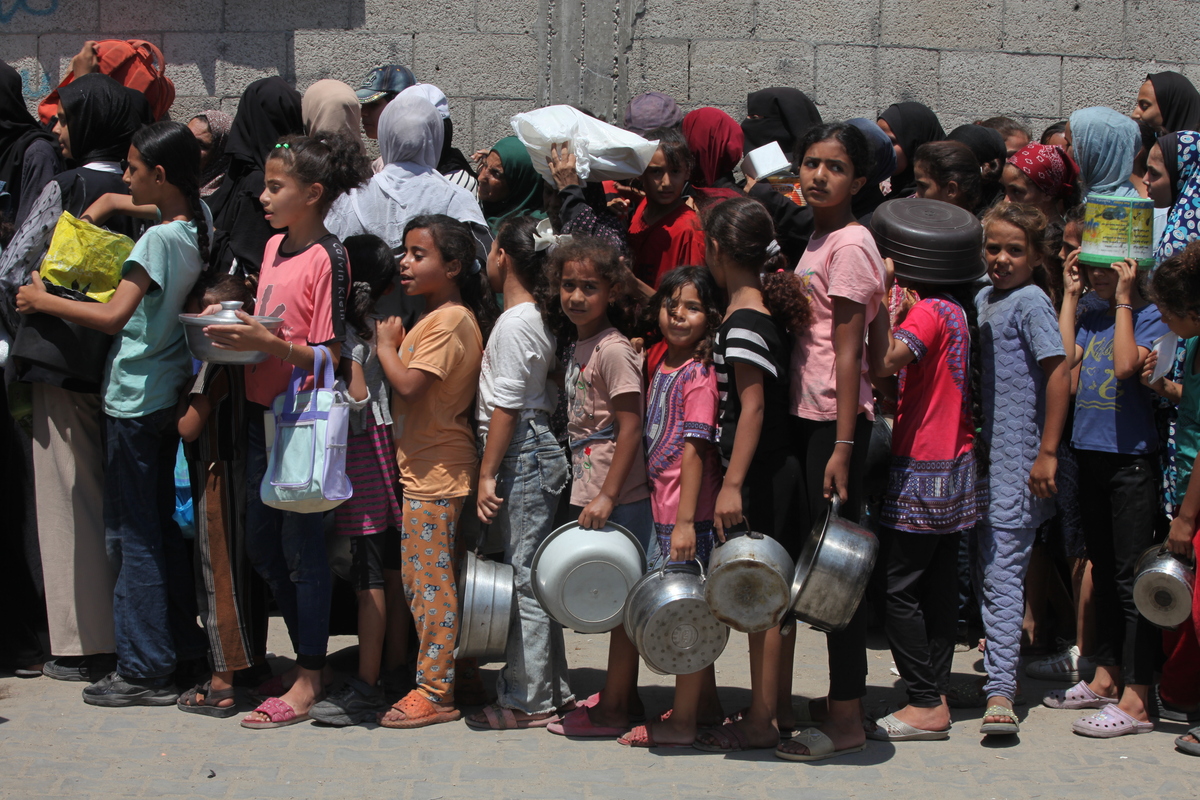 Palestinians, including children, who are struggling to access food due to Israel's blockade and ongoing attacks on the Gaza Strip, wait in line to receive hot meals distributed by the charity organization at the Nuseirat refugee camp in Deir al-Balah, Gaza on August 18, 2025. [Moiz Salhi - Anadolu Agency]