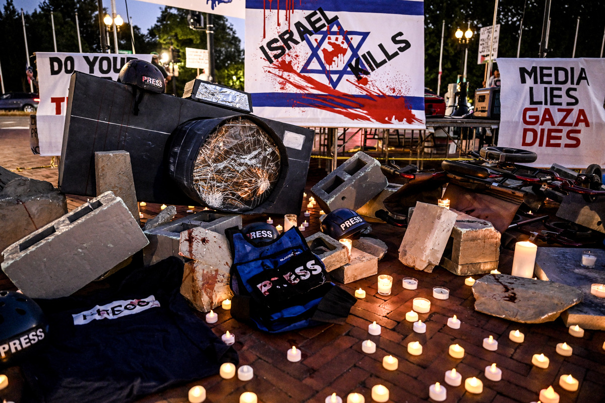 Protesters placed broken cameras, helmets marked with “PRESS,” blood-stained protective vests, and scattered cinder blocks on the ground surrounded by candles during an emergency demonstration in front of Union Station in Washington, D.C., on August 28, 2025. [Fatih Aktaş - Anadolu Agency]