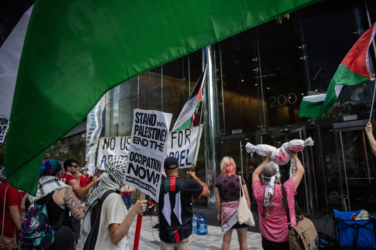 Pro-Palestinian demonstrators bang pots and pans and bang on the entrance doors to the Boston Consulting Group building during a "Stop starving Gaza" protest and rally in Boston, Massachusetts on July 25, 2025. [Photo by JOSEPH PREZIOSO/AFP via Getty Images]