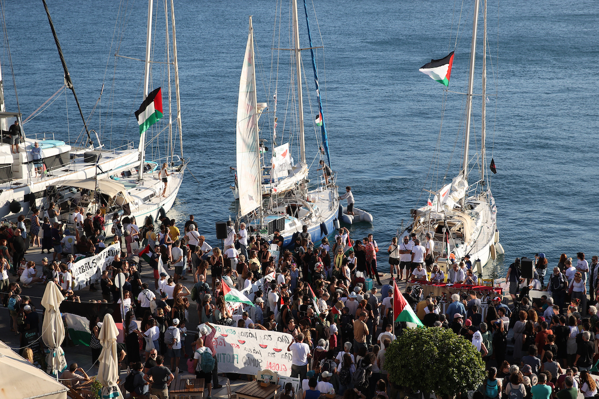 Supporters gather at the port in Syros, Greece, waving Palestinian flags as boats depart to join the Global Sumud Flotilla sailing toward Gaza in an effort to break the Israeli policy and show solidarity with the Palestinian people, on September 14, 2025. [Ayhan Mehmet - Anadolu Agency]