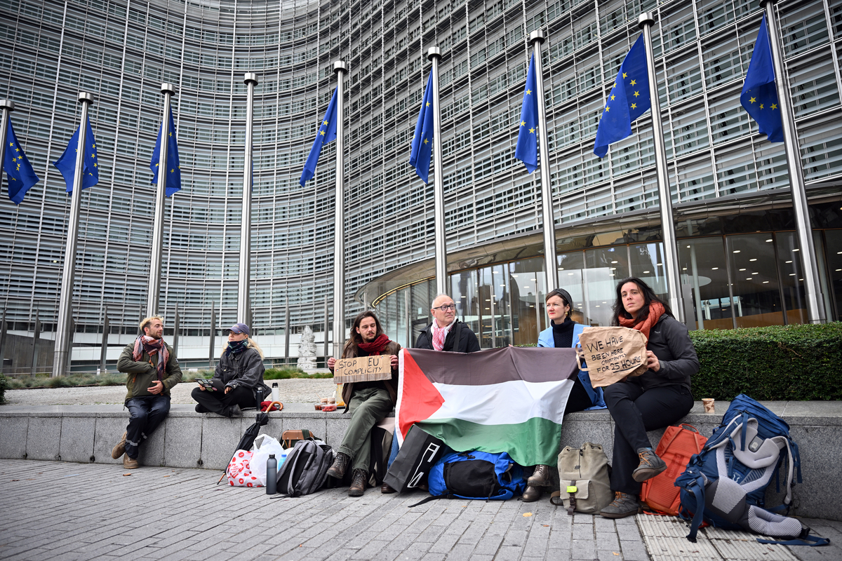 Protesters hold a Palestinian flag and a sign reading “We have been here constantly for 25 hours” outside the European Commission building, calling on the EU to maintain pressure on Israel despite the ceasefire and to hold Tel Aviv accountable for war crimes, in Brussels, Belgium, on October 20, 2025. [Dursun Aydemir - Anadolu Agency]