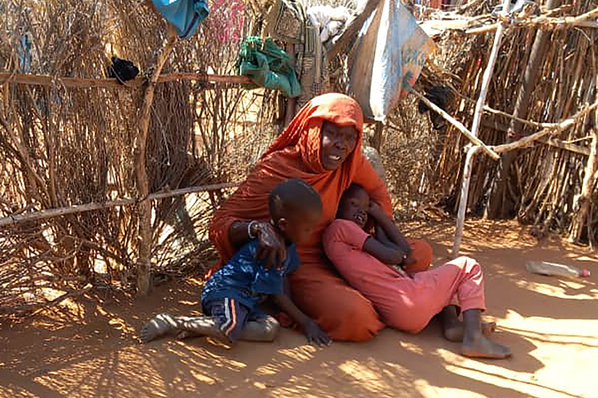 Displaced Sudanese mother Mona Ibrahim and her children sit on the ground in the famine-stricken Zamzam camp for Internally Displaced Persons (IDP) in northern Darfur on January 21, 2025. [Photo by -/AFP via Getty Images]