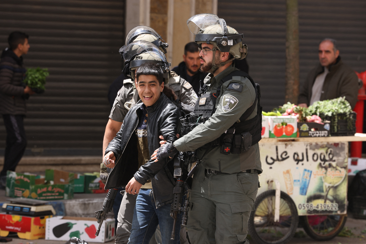 Israeli army soldiers detain a Palestinian boy after he threw rocks ahead of a visit by Ultra-Orthodox Jews to the shrine of Atnaeil Ben Kinaz in the city of Hebron in the Israeli-occupied West Bank on April 16, 2025. [Photo by HAZEM BADER/AFP via Getty Images]